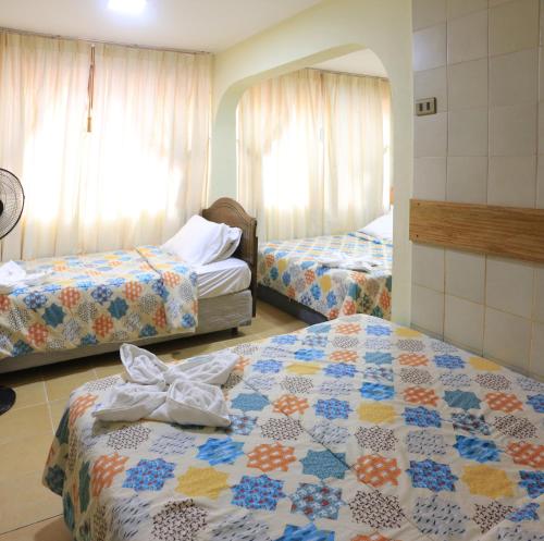 a hotel room with two beds and two windows at Hotel Garden Latorre in Iquique