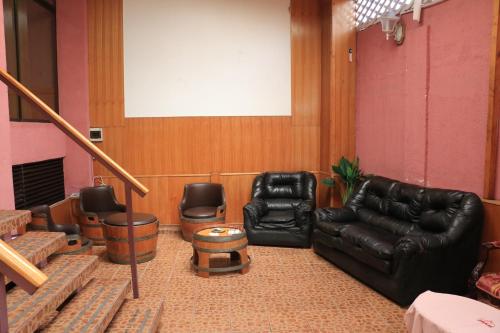 a living room with black leather furniture and a whiteboard at Hotel Garden Latorre in Iquique