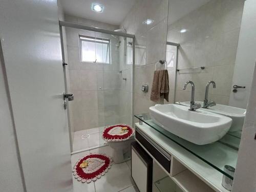 Un baño blanco con lavabo y ducha. en Apartamento Capivari de Baixo, en Capivari de Baixo