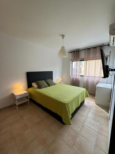 a bedroom with a bed with a green bedspread at Sunflower Apartment in Armação de Pêra