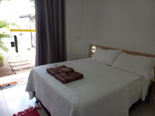 a bed with two brown towels on top of it at AYRE GOSTOSO POUSADA in São Miguel do Gostoso