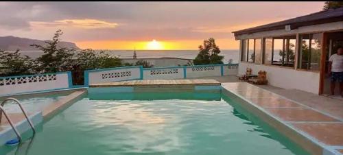 a swimming pool with a sunset in the background at Casa Montemar Hotel-San Vicente in San Vicente