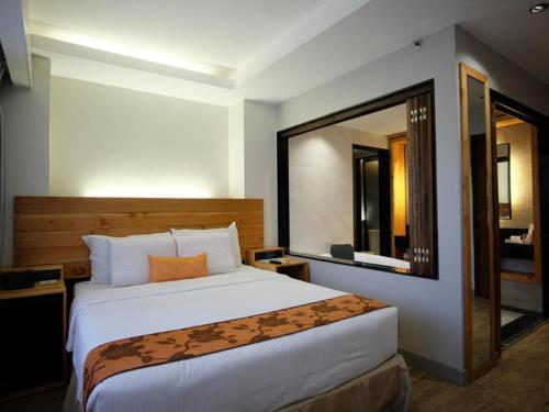 a bedroom with a large bed and a large mirror at Cuarto Hotels Cebu in Cebu City