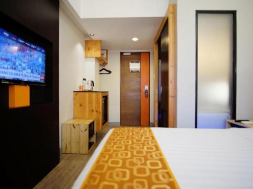 a hotel room with a bed and a flat screen tv at Cuarto Hotels Cebu in Cebu City