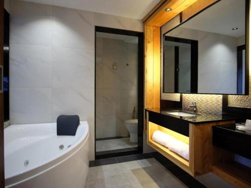 a bathroom with a tub and a sink and a mirror at Cuarto Hotels Cebu in Cebu City