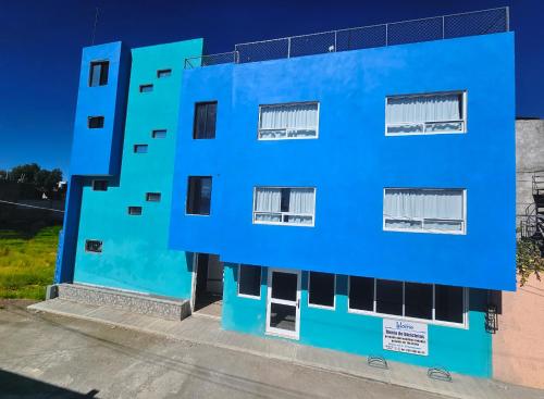 a blue building with black windows on a street at Sensity Home Recamara moderna in Tehuacán