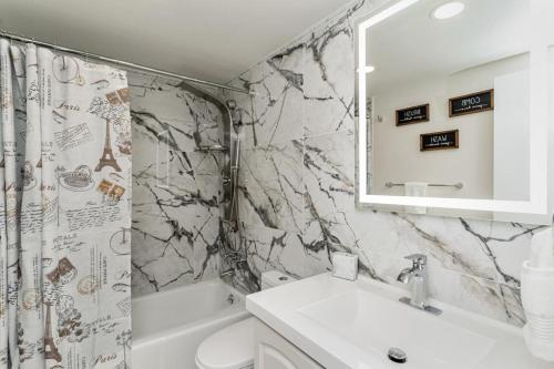 ein weißes Badezimmer mit einem Waschbecken und einem Spiegel in der Unterkunft Beachfront Modern 5 Stars 1 Bedroom Apartment in Hollywood