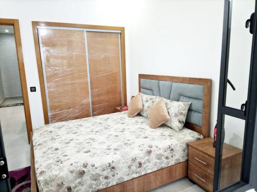 a bedroom with a bed with a wooden headboard at Appartement de luxe in Kenitra