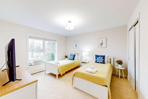 een slaapkamer met 2 bedden en een flatscreen-tv bij Blooming Sunshine - Unit 1 in East Falmouth
