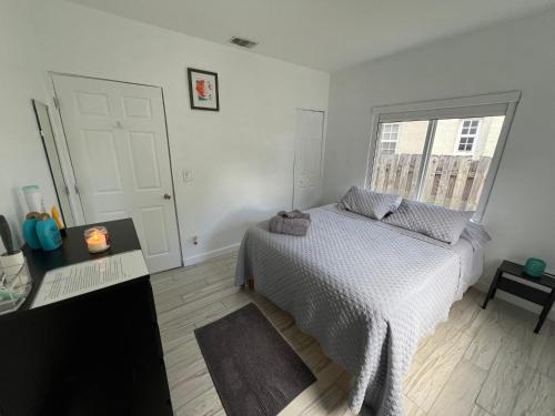 a white bedroom with a bed and a window at Cozy room in a quiet home in Miami