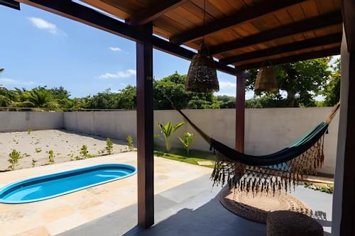 a hammock on a patio next to a pool at Casa com piscina na tranquilidade de Barra Grande in Barra Grande