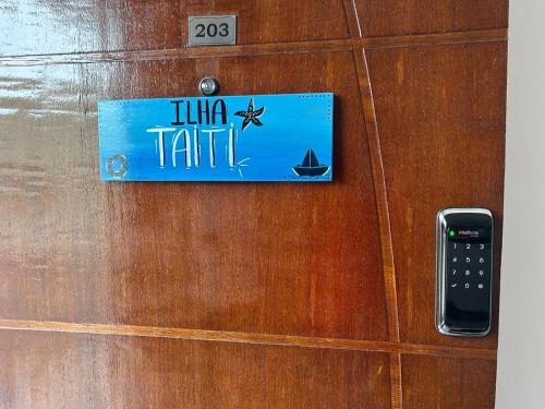 a sign on a wooden door with a remote control at BORA BORA RESIDENCE in Joinville
