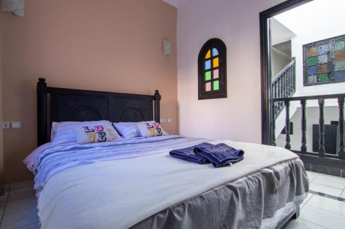 um quarto com uma cama com lençóis azuis e uma janela em RIAD TAWSALANE em Marrakech