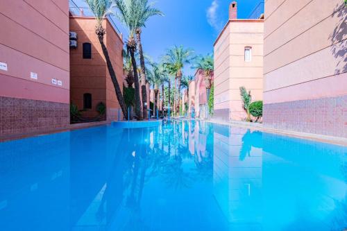 a swimming pool between two buildings with palm trees at RIAD TAWSALANE in Marrakech