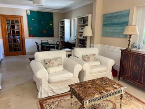 a living room with two white chairs and a table at Herdade de Santa Maria in Almeirim