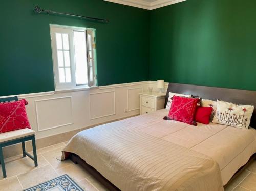 a green bedroom with a large bed with red pillows at Herdade de Santa Maria in Almeirim