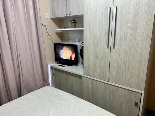 um quarto com uma cama e uma televisão num quarto em Apartamento bem localizado em Cabo Frio