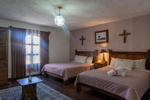 a bedroom with two beds and a cross on the wall at Hotel Refugio Victoria in Morelia
