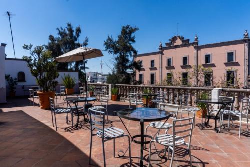 a patio with tables and chairs and an umbrella at Hotel Refugio Victoria in Morelia