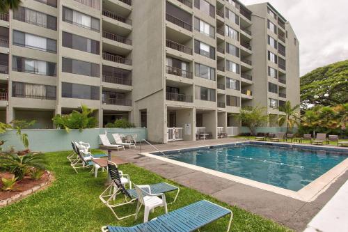 an apartment building with a swimming pool and lounge chairs at Ocean view Mauna Loa Shores Kai Ekahi #201 next to Carlsmith Beach Park Hilo HI in Hilo