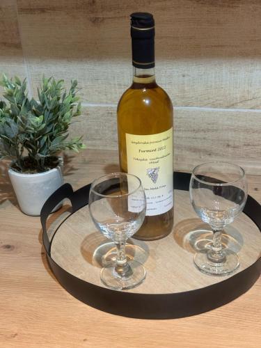 a bottle of wine and two wine glasses on a tray at Tokajský domček in Malá Tŕňa