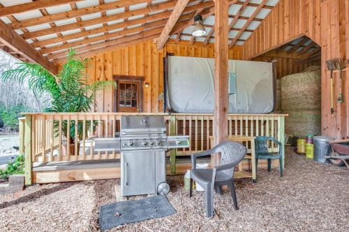 a wooden building with a stove and a tv at Clarkesville Rustic Hideaway on 38-Acre Farm! in Clarkesville
