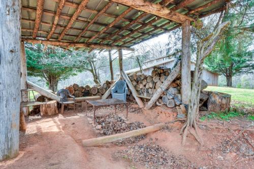 a pile of logs sitting under a shed at Clarkesville Rustic Hideaway on 38-Acre Farm! in Clarkesville