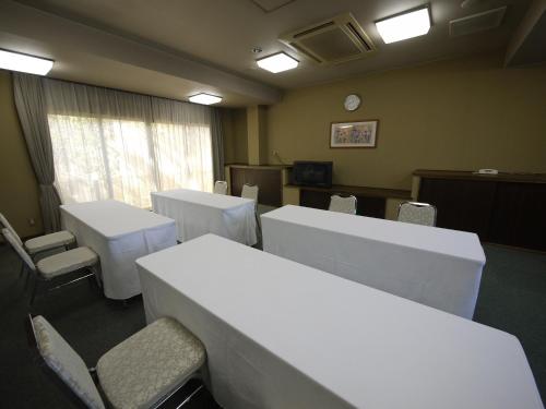 a room with white tables and chairs and a clock at Hotel Route-Inn Court Uenohara in Uenohara
