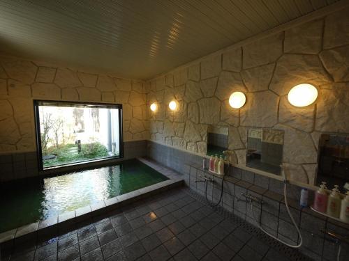 a bathroom with a swimming pool with a window at Hotel Route-Inn Court Uenohara in Uenohara