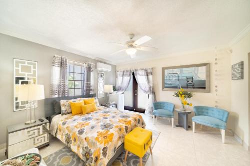 a bedroom with a bed and two blue chairs at Hidden Gem Barbados in Christ Church
