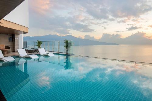 a swimming pool with chairs and a view of the water at Radisson Hotel Danang in Danang