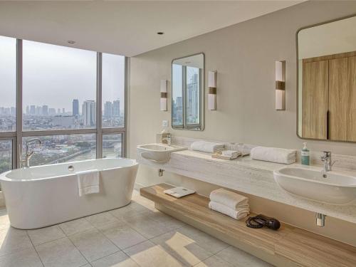 a bathroom with two sinks and a tub and mirrors at Novotel Suites Manila at Acqua in Manila