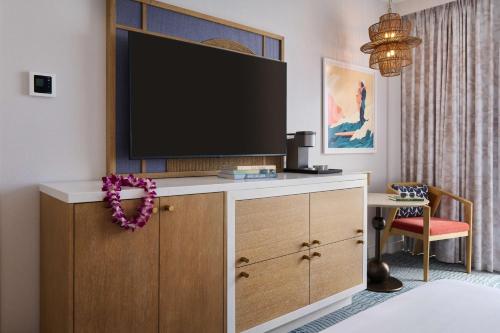 a room with a tv on top of a dresser at OUTRIGGER Waikiki Paradise Hotel in Honolulu