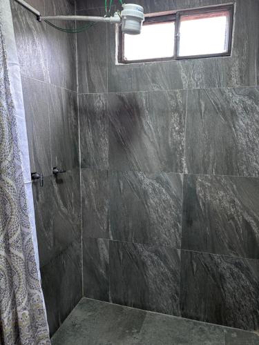uma casa de banho com um chuveiro e uma parede de pedra em Baños De Agua Santa em Baños