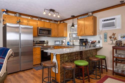 a kitchen with a stainless steel refrigerator and bar stools at Waterfront Cabin 20 Mins to National Park & Massanutten! in Stanardsville