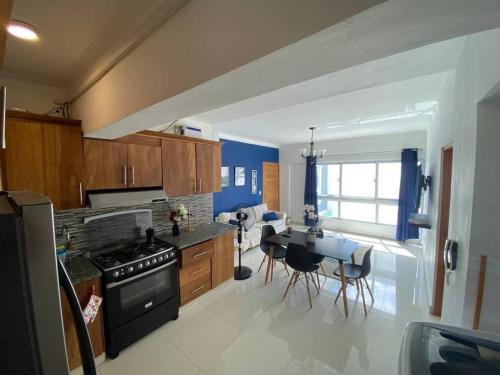 a kitchen with a stove and a table with chairs at Modesto y Acogedor Apartamento en Costa Verde in Santo Domingo