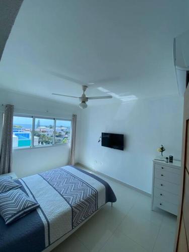 a white bedroom with a bed and a ceiling fan at Modesto y Acogedor Apartamento en Costa Verde in Santo Domingo