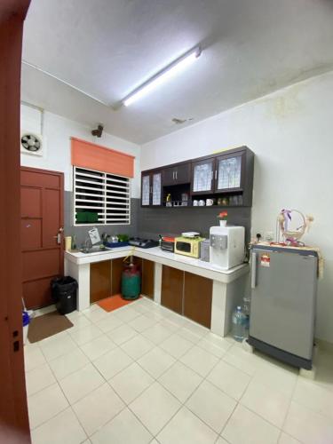 a large kitchen with a counter and a refrigerator at HOMESTAY DSENJA in Kepala Batas