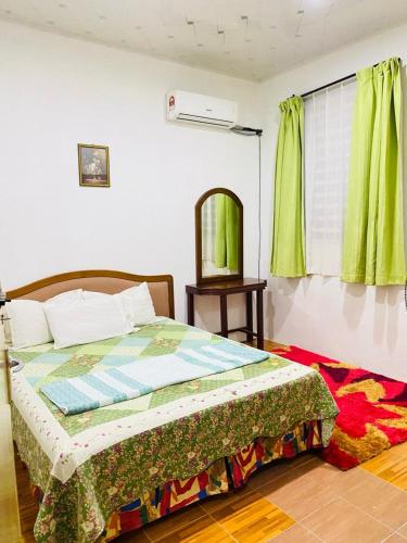 Schlafzimmer mit einem Bett und einem Fenster mit grünen Vorhängen in der Unterkunft HOMESTAY DSENJA in Kepala Batas