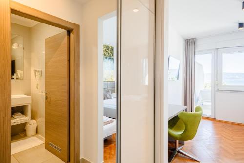 a bathroom with a green chair in front of a door at Rogač Rooms & Restaurant in Omiš