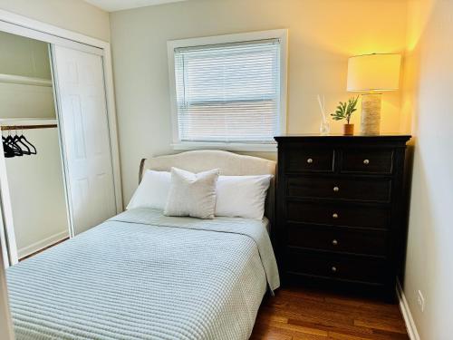 a bedroom with a bed with a dresser and a window at Charming and Convenient 3br 1ba apt - fully furnished and equipped - fast Internet in Forest Park