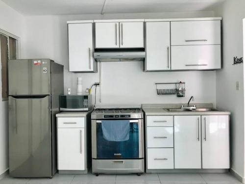 una cocina con electrodomésticos de acero inoxidable y armarios blancos en Hermosa y Confortable, Petfriendly ¡Facturamos!, en Durango