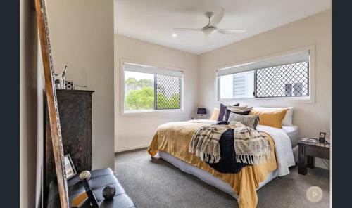 a bedroom with a bed and two windows at Salt Zen Holiday Townhouse in Agnes Water