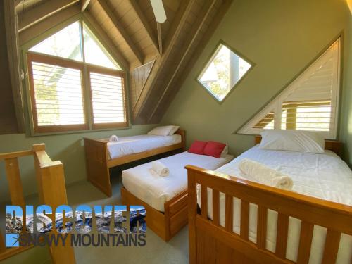 a attic bedroom with two beds and two windows at Mitta Mitta in Thredbo