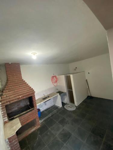 a kitchen with a brick fireplace in a room at Casa na praia, 15 min de caminhada in Itanhaém