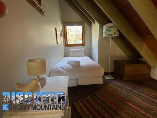 a small bedroom with a bed and a window at Bollygums in Thredbo