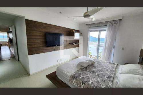 um quarto com uma cama e uma televisão de ecrã plano em Apto gigante alto padrão de frente para o MAR em Santos