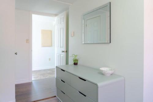 a white bedroom with a dresser and a mirror at Amazing location in Saint John 2 Br Modern Parking New in Saint John