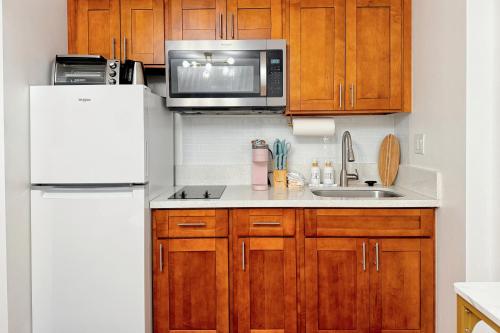 a kitchen with wooden cabinets and a white refrigerator at 1BR Ocean Sunset View With Parking in Honolulu
