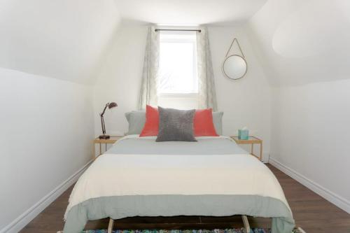 Schlafzimmer mit einem Bett mit roten Kissen und einem Fenster in der Unterkunft Amazing location in Saint John 2 Br Modern Parking New in Saint John